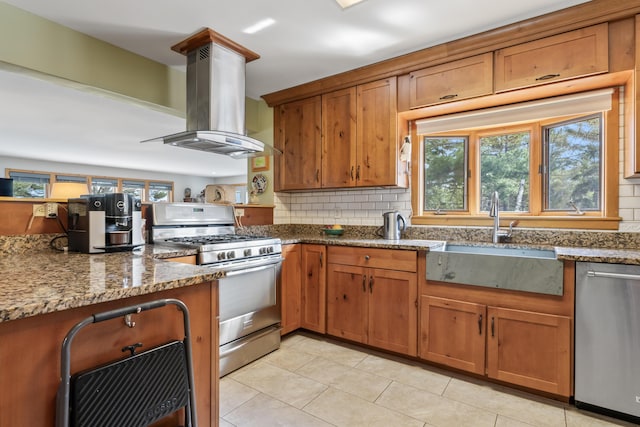 kitchen with brown cabinets, a sink, appliances with stainless steel finishes, and island exhaust hood