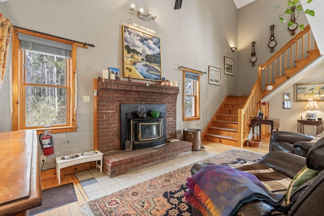 tiled living area with a wood stove, a towering ceiling, and stairway