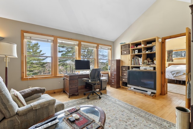 home office with high vaulted ceiling and light wood-style flooring