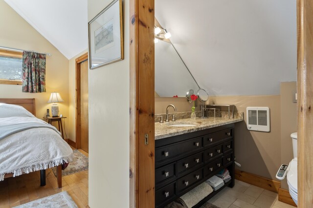 bathroom with vanity, heating unit, toilet, baseboards, and vaulted ceiling