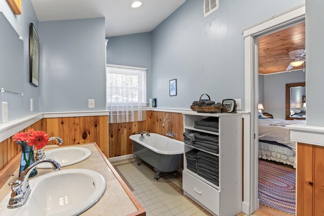 bathroom with a sink, a freestanding bath, wainscoting, and visible vents