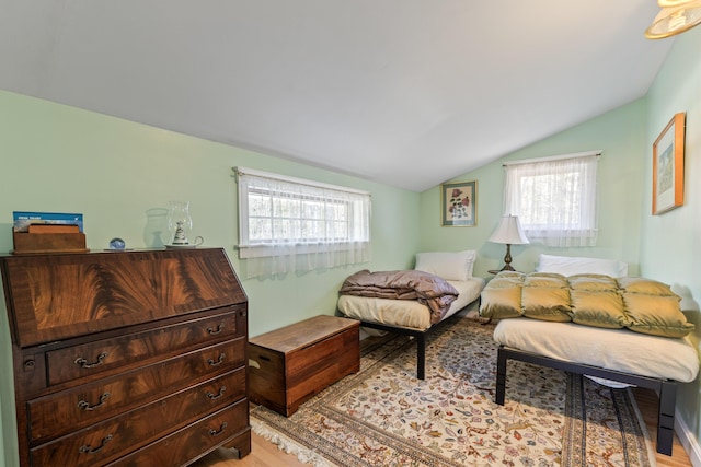bedroom featuring light wood-style floors, multiple windows, and lofted ceiling