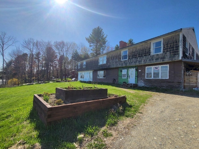 exterior space with a lawn, a vegetable garden, a chimney, and entry steps