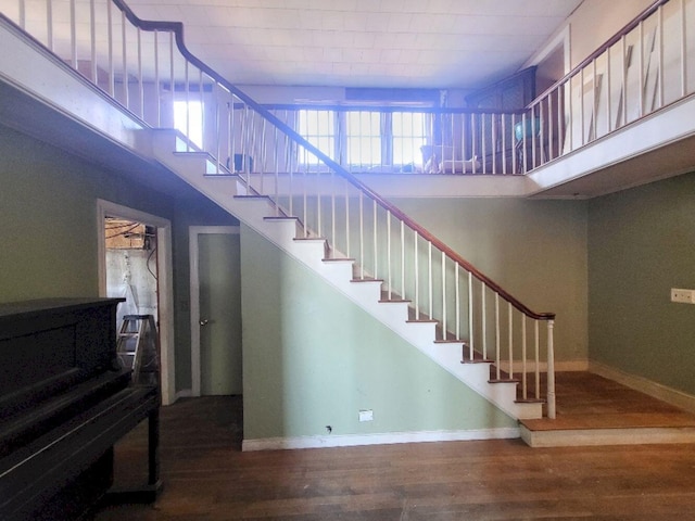 stairs featuring baseboards, a towering ceiling, and wood finished floors