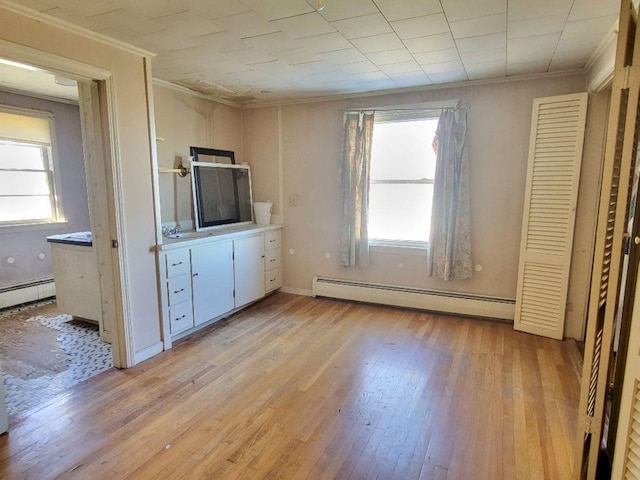 unfurnished bedroom with a baseboard radiator, light wood-style flooring, and ornamental molding