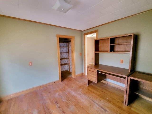 unfurnished office with light wood-type flooring, ornamental molding, and baseboards