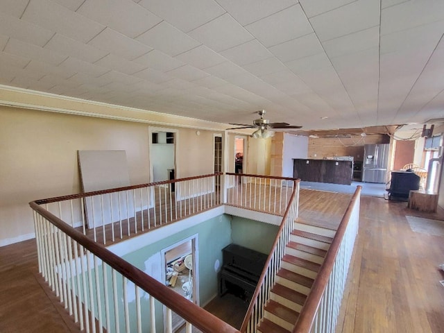 staircase featuring baseboards, ceiling fan, ornamental molding, and wood finished floors