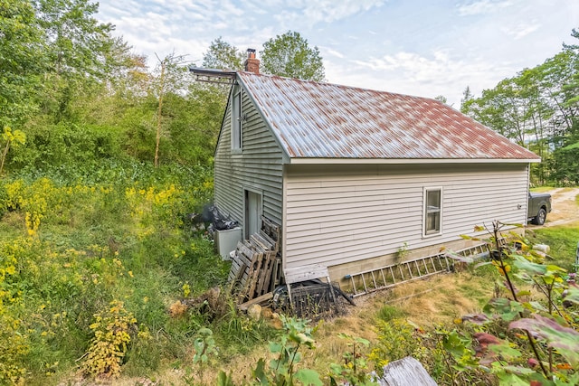 view of side of home featuring a chimney and metal roof