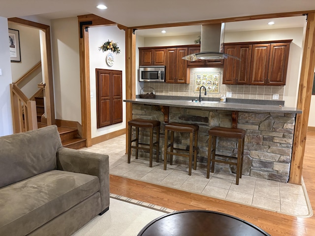 1 Mccracken Ln, Bristol, ME 04539 - kitchen featuring stainless steel microwave, range hood, a breakfast bar, light wood-style floors, and a sink