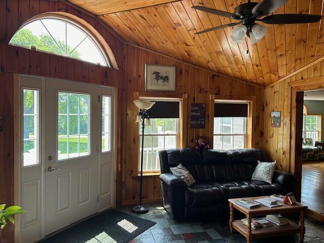 living room featuring wooden walls, wooden ceiling, and vaulted ceiling