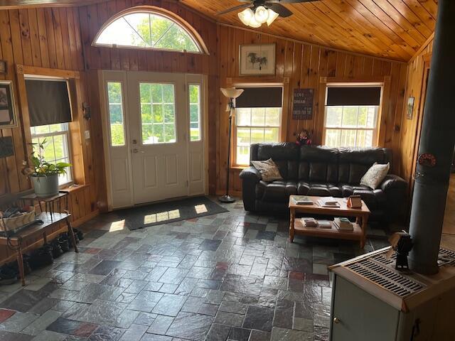 living area featuring plenty of natural light, vaulted ceiling, and wood walls