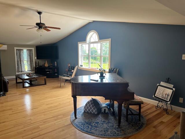 home office featuring light wood-style flooring, ceiling fan, vaulted ceiling, and a wealth of natural light
