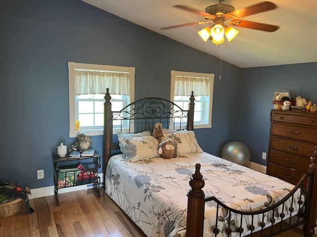 bedroom with wood finished floors, baseboards, ceiling fan, and lofted ceiling