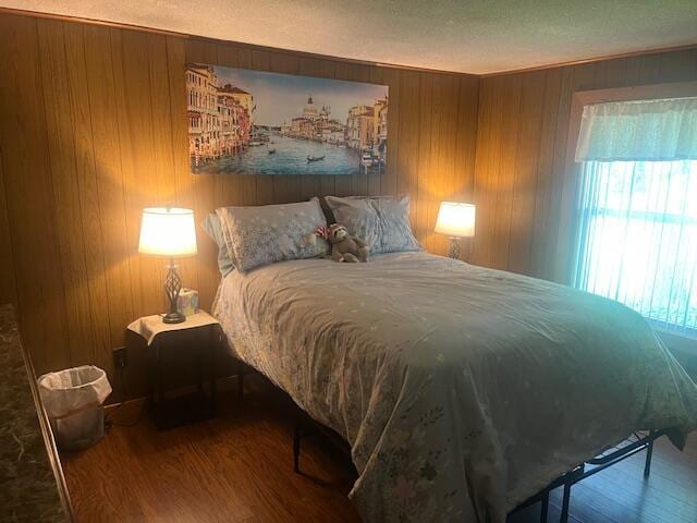 bedroom with wooden walls, multiple windows, and wood finished floors