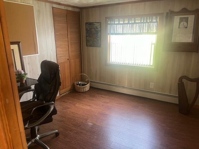 home office featuring wood walls, baseboard heating, and wood finished floors
