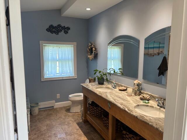 full bath with double vanity, toilet, baseboards, and a sink