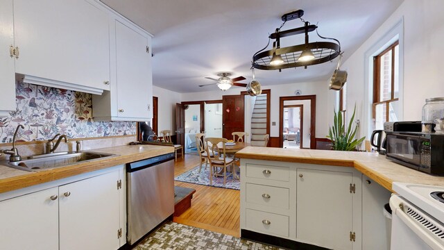 kitchen featuring black microwave, a sink, dishwasher, a peninsula, and a ceiling fan