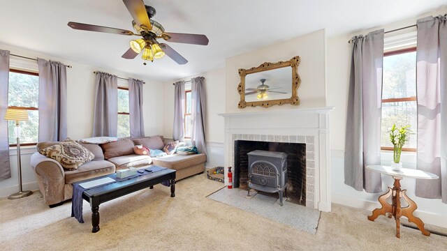 carpeted living room with a ceiling fan and a wood stove