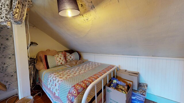 bedroom with wood finished floors and lofted ceiling