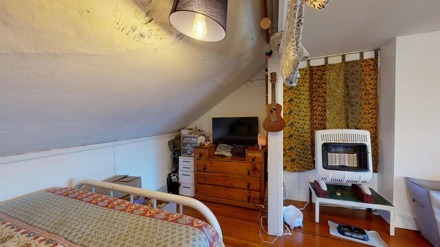 bedroom featuring heating unit, wood finished floors, and lofted ceiling