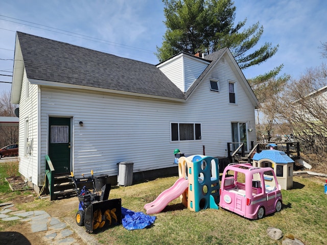 back of property featuring a shingled roof, a playground, a yard, and entry steps