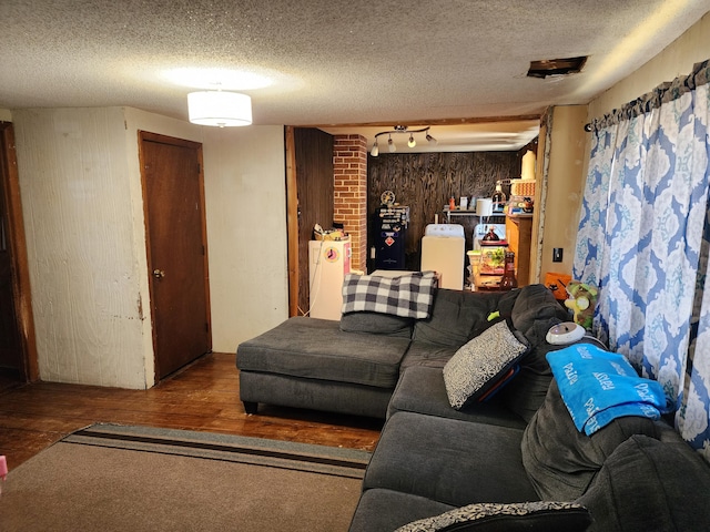 living room with washing machine and clothes dryer, wooden walls, a textured ceiling, and wood finished floors