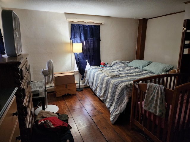 bedroom featuring a baseboard heating unit and hardwood / wood-style floors