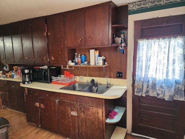 kitchen with light countertops, open shelves, black microwave, and a sink
