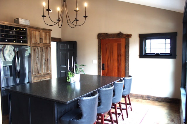 kitchen featuring brown cabinets, dark countertops, black fridge, baseboards, and a kitchen island