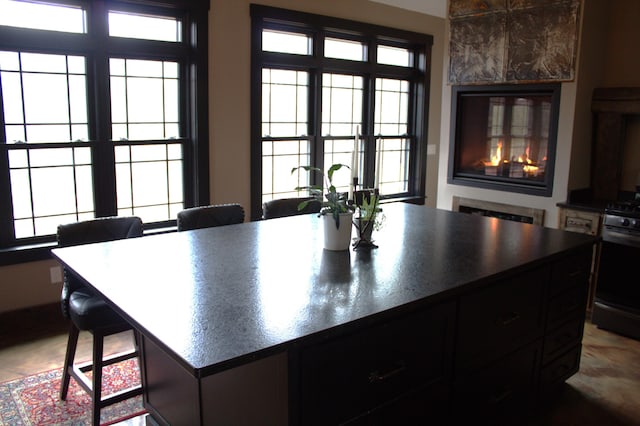 kitchen with dark countertops, open floor plan, a breakfast bar area, range with gas cooktop, and dark cabinets