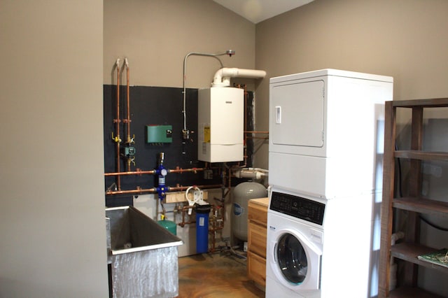 washroom with laundry area, stacked washing maching and dryer, a sink, and water heater