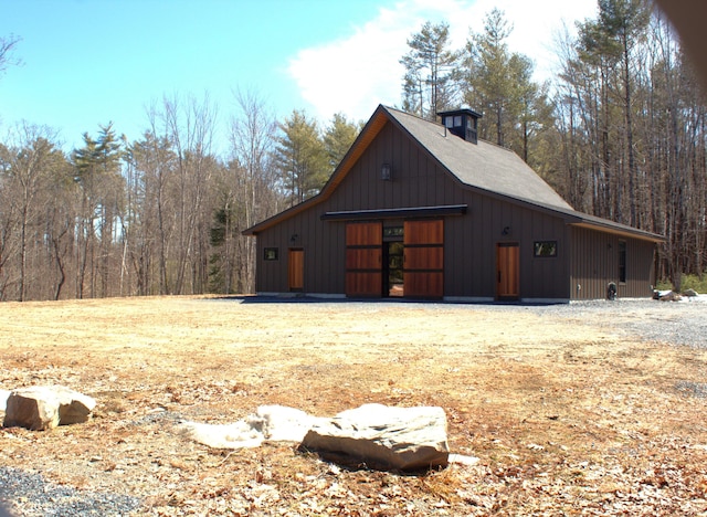 view of side of property with a detached garage, a pole building, an outbuilding, and board and batten siding
