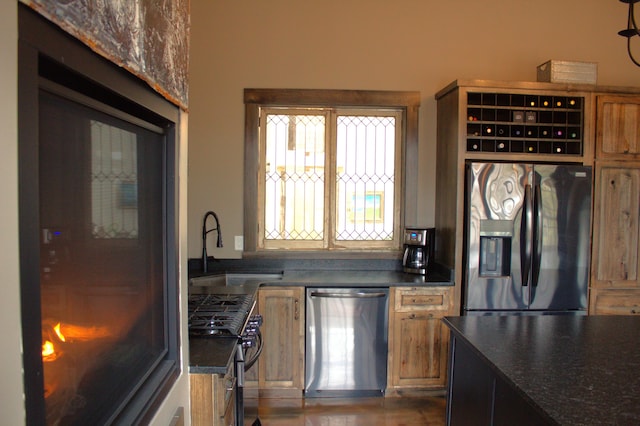 kitchen featuring dark countertops, appliances with stainless steel finishes, brown cabinetry, and a sink