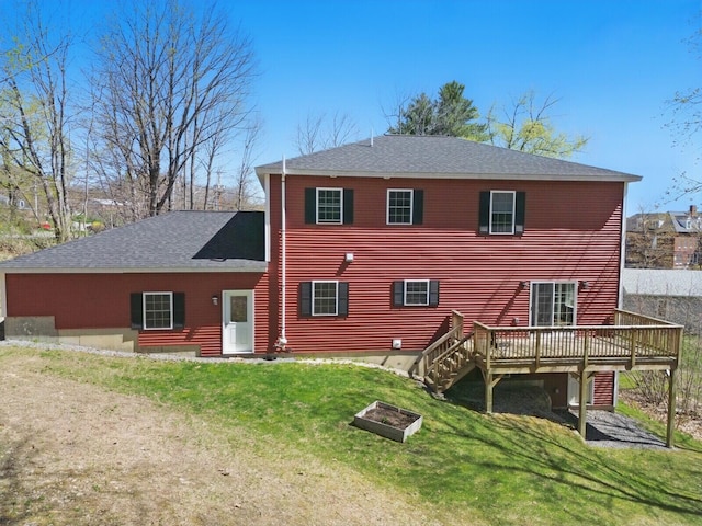 back of house with a yard, roof with shingles, and a deck