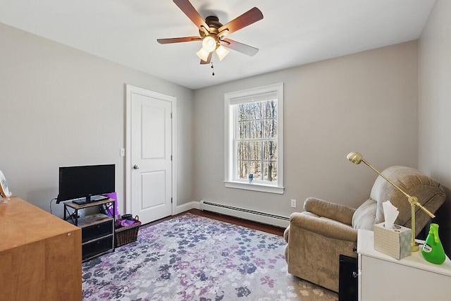 sitting room with a ceiling fan, a baseboard radiator, baseboards, and wood finished floors