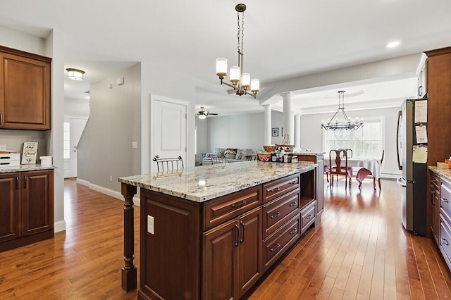 kitchen with a breakfast bar, freestanding refrigerator, and dark wood finished floors
