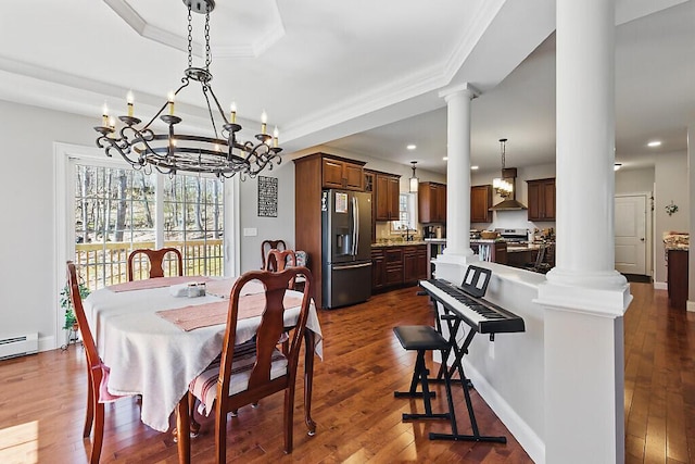 dining room featuring crown molding, a tray ceiling, a chandelier, and decorative columns