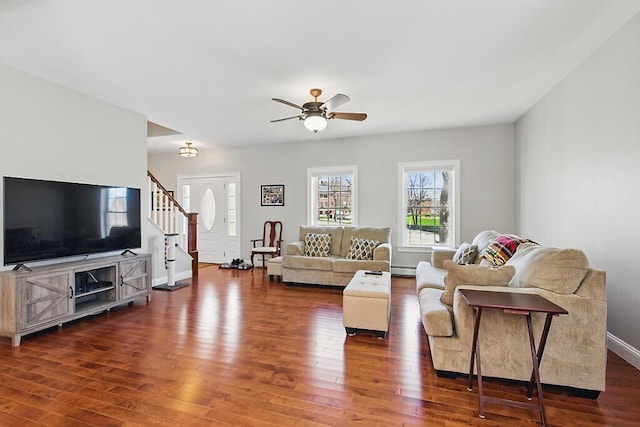 living area with ceiling fan, stairs, baseboards, and dark wood-type flooring