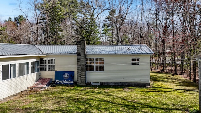 rear view of house with a yard, a chimney, and metal roof