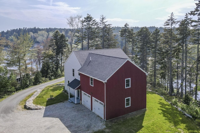 20 Campbell Rd, Southport, ME 04576 - view of property exterior with gravel driveway, roof with shingles, a view of trees, a garage, and a yard