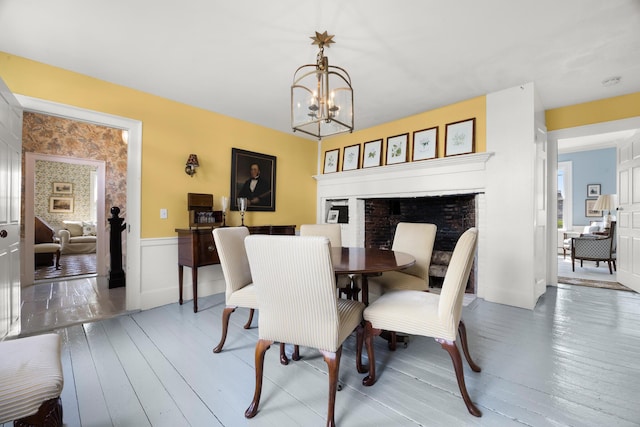 197A Perkins St, Castine, ME 04421 - dining area featuring a chandelier, wood finished floors, a fireplace, and wainscoting
