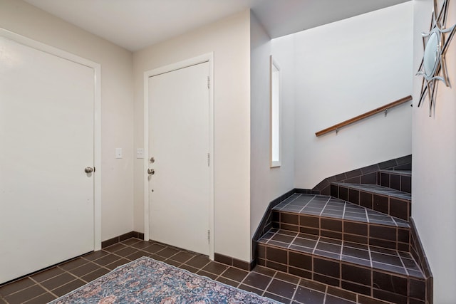 entryway with dark tile patterned flooring and baseboards