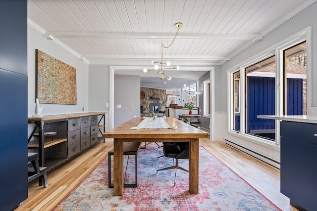 dining area with baseboard heating, beamed ceiling, light wood finished floors, and a chandelier