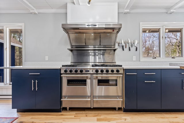 kitchen featuring light countertops, light wood finished floors, blue cabinets, and range with two ovens