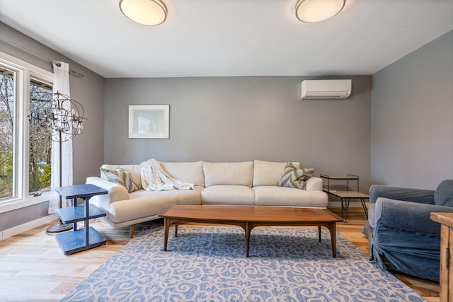 living area with plenty of natural light, a wall mounted air conditioner, baseboards, and light wood finished floors