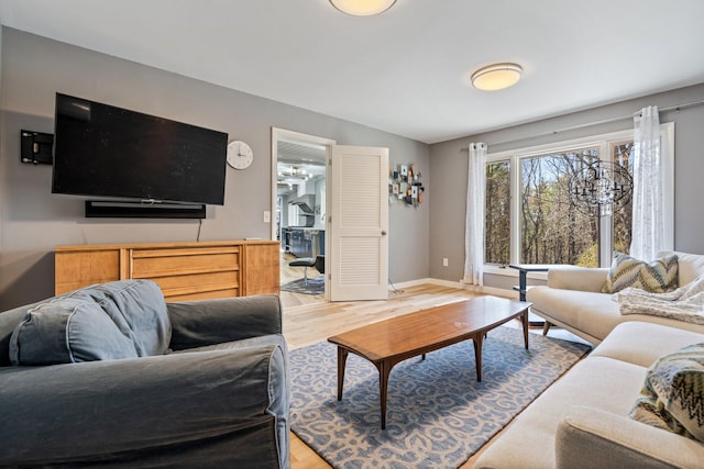 living area with baseboards, lofted ceiling, and light wood-style floors