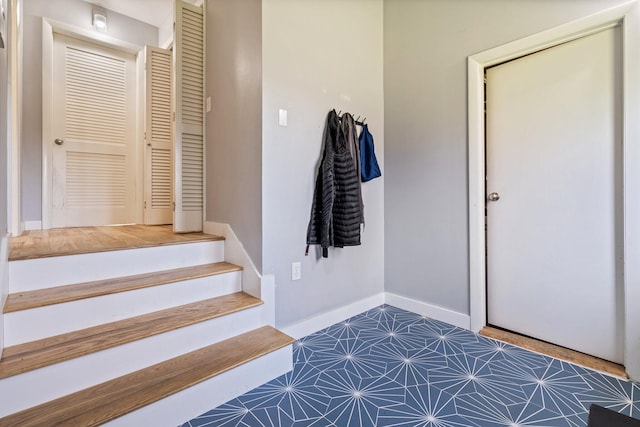 foyer entrance with stairway and baseboards