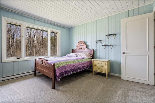 carpeted bedroom with baseboard heating and wood walls
