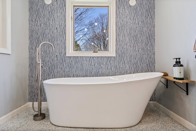 bathroom featuring a freestanding tub and baseboards