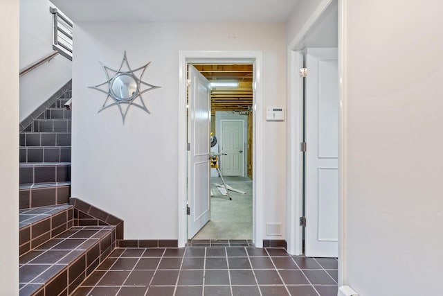 corridor featuring dark tile patterned flooring, baseboards, and visible vents